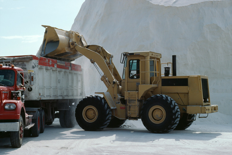 Bulldozer loader pouring salt into truck